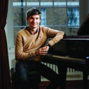 Member John Paul Muir by a piano at Goodenough College
