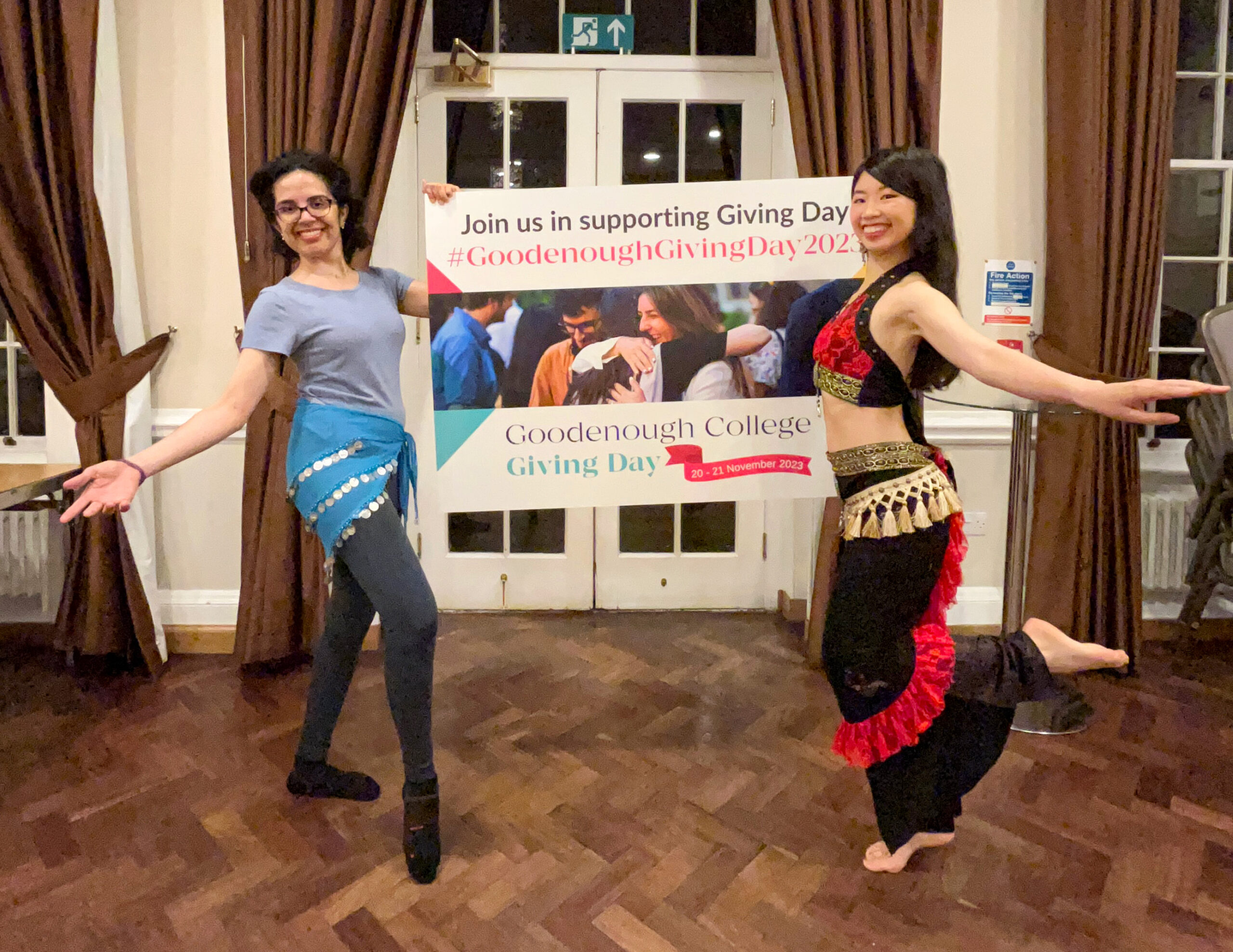 Goodenough Belly Dancing Club Members hold a Goodenough Giving Day 2022 foam board
