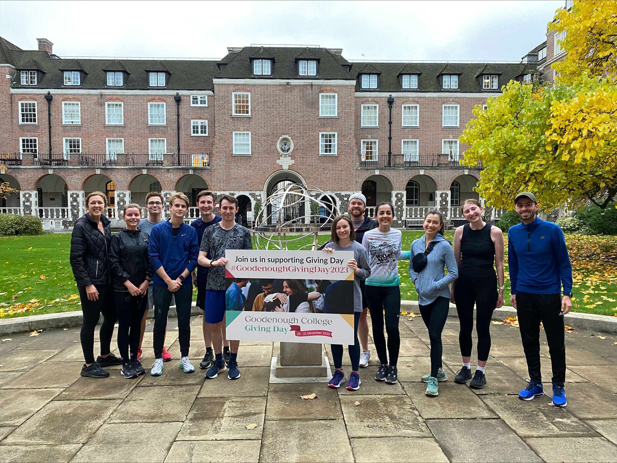 Group of Goodenough College runners in the courtyard with a Goodenough Giving Day sign